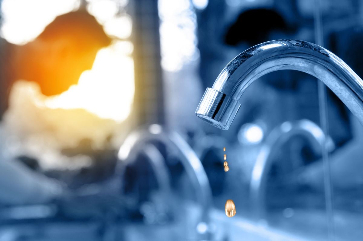 A drop of water falling from a chrome kitchen tap